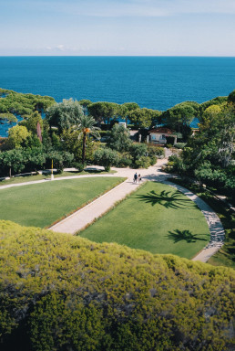 Jardin méditerranéen Four Seasons Cap Ferrat avec pelouse, palmiers et vue panoramique mer