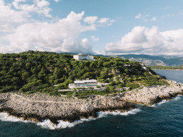 Spectacular aerial view of Four Seasons Cap Ferrat on rocky Mediterranean promontory with mountains