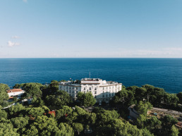 Vue aérienne d'un hôtel blanc de luxe niché dans une colline verdoyante surplombant la mer Méditerranée bleue