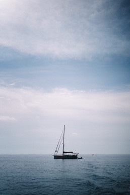 Voilier solitaire naviguant sur mer Méditerranée sous ciel nuageux en Sicile
