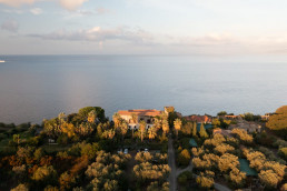 Vue aérienne coucher de soleil sur villa sicilienne en pierre entourée d'orangers avec vue mer Méditerranée