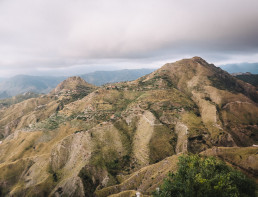Panoramic aerial view of arid Sicilian mountains with green hills, hilltop villages and dramatic cloudy skies