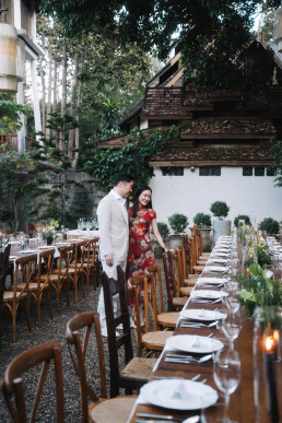 Couple at romantic dinner table under illuminated traditional Thai Four Seasons wooden pavilion