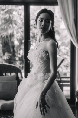 Black and white portrait of Asian bride in strapless dress in front of Four Seasons light window
