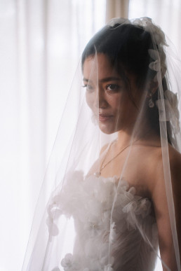 Asian bride portrait with transparent veil and coiffed bun looking towards the light