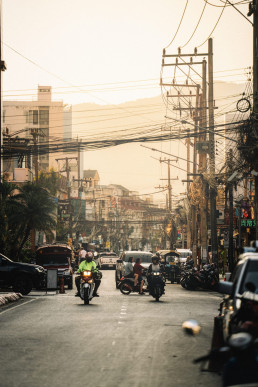 Busy Chiang Mai street with motorcycles, electric cables and Thai urban architecture