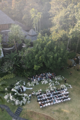 Aerial view of outdoor wedding ceremony with white floral arch and rows of Four Seasons chairs