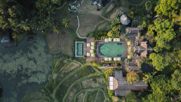 Drone view of lakeside wedding ceremony with rice paddies and traditional Thai architecture