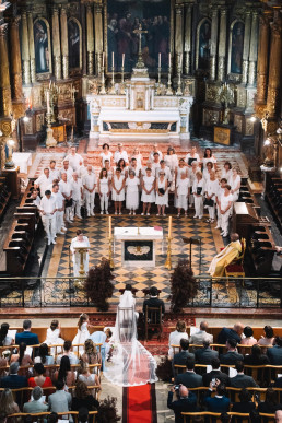 Vue plongeante cérémonie de mariage dans église baroque avec chorale et invités en blanc