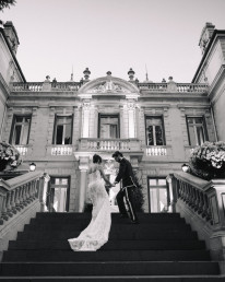 Couple de mariés sur escalier monumental en noir et blanc devant château classique