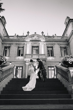 Couple de mariés sur escalier monumental en noir et blanc devant château classique