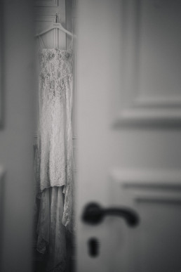 Robe de mariée en dentelle blanche suspendue à cintre sur porte vintage