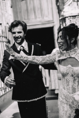 Bride and groom in black and white walking in the interior corridor of the château, bride in lace dress