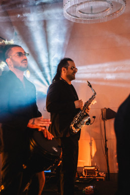 Live wedding performance with saxophonist and DJ under colorful spotlights