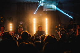 Groupe d'invités dansant dans l'obscurité entourés de fontaines de feu d'artifice étincelantes projetant des étincelles dorées
