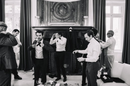 Preparations for the groom and witnesses adjusting their costumes in a Belle Époque salon