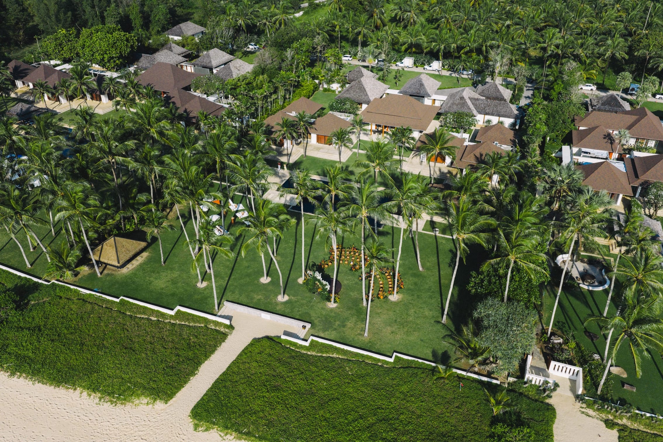 Drone view of luxury villas surrounded by palm trees near the beach in Phuket