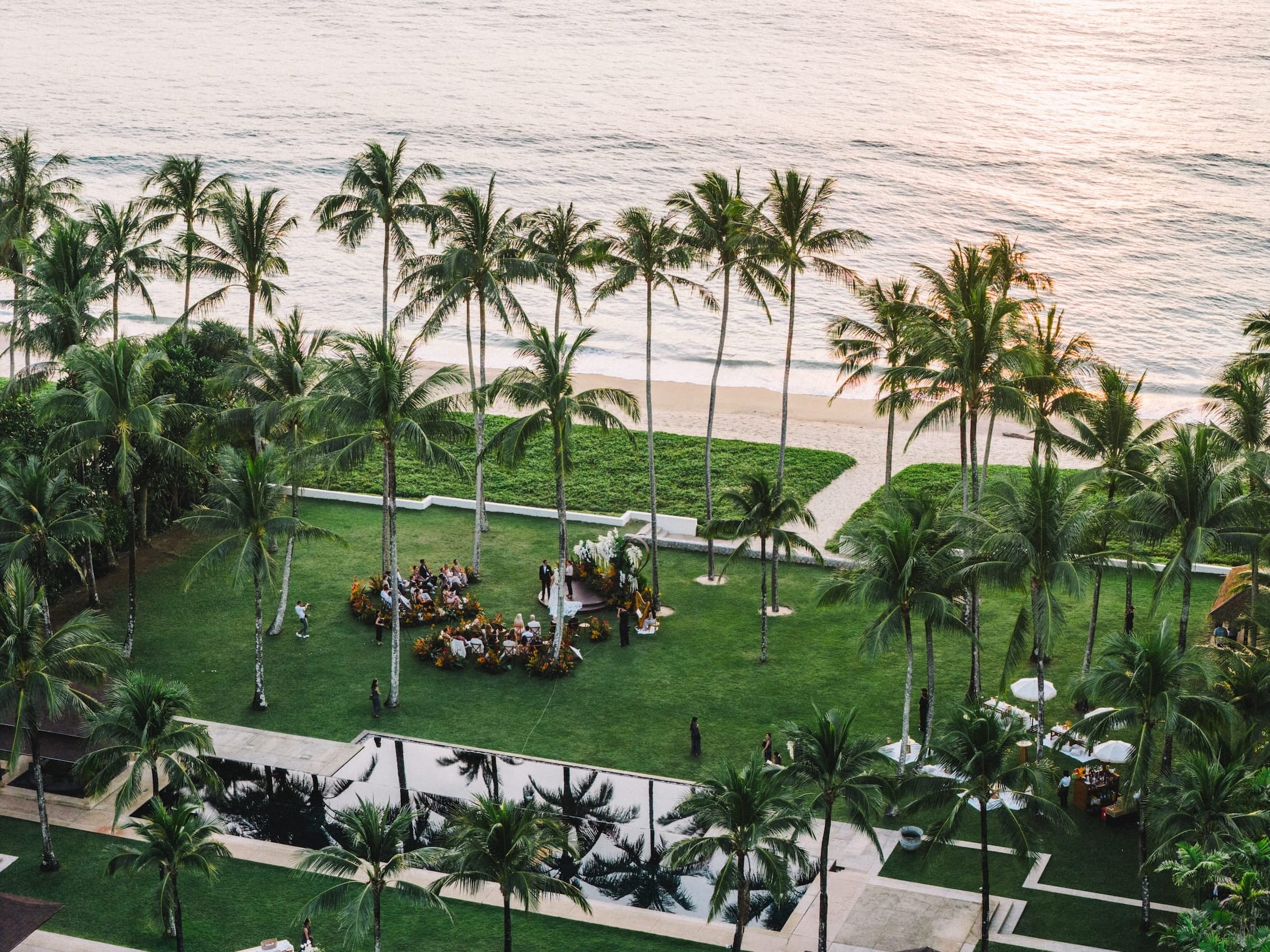 Aerial view of tropical beachfront wedding ceremony setup surrounded by palm trees in Phuket
