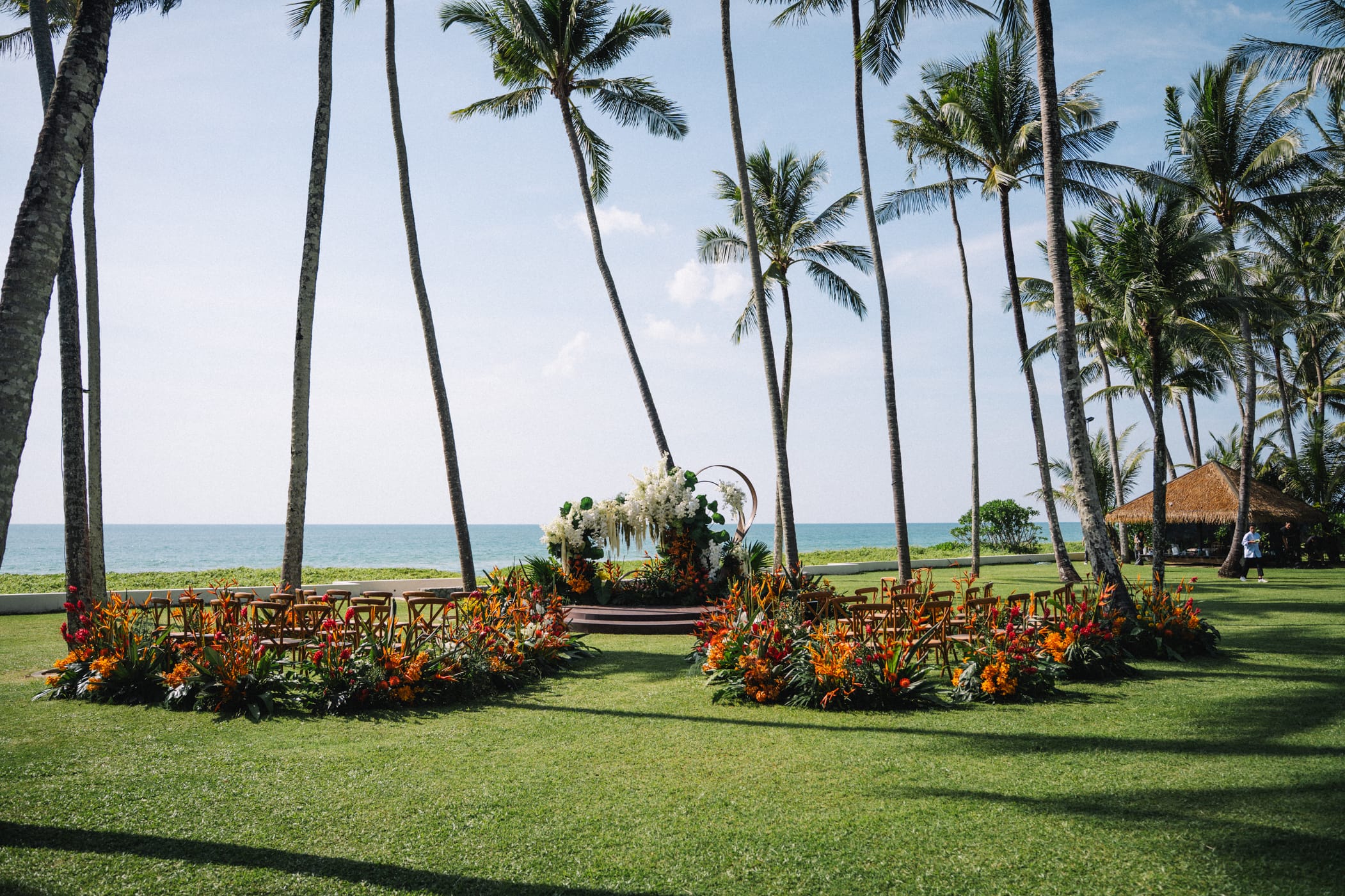 Tropical wedding ceremony arch decorated with colorful flowers facing the ocean