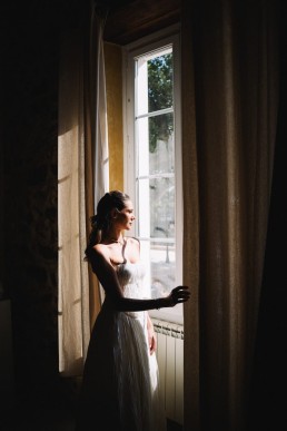 Une mariée qui attend le début de la cérémonie laïque près de la fenêtre au Clos du Tuilier dans le sud de la France