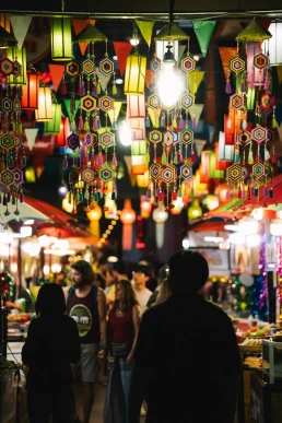 Couple walking through a colourful night market during their elopement in Chiang Mai, Thailand