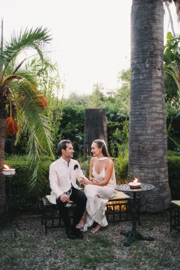 Couple sharing a relaxed outdoor meal beneath palm trees during their elopement in Italy