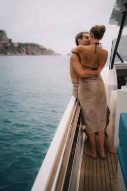 Couple embracing on a boat during a coastal elopement in Italy