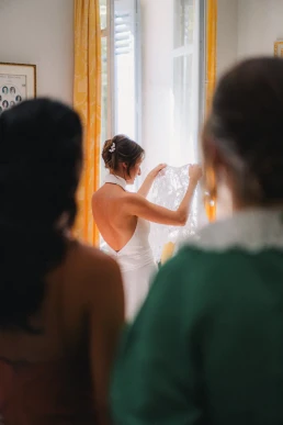 Bride seen through a doorway while preparing beside a window at Château Valmousse