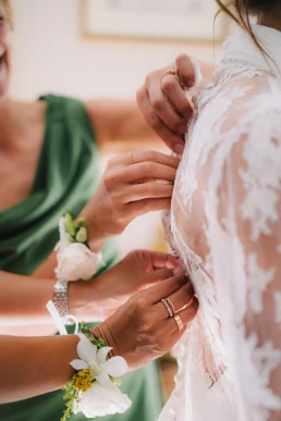 Bridesmaid fastening a floral wrist corsage during preparations at Château Valmousse
