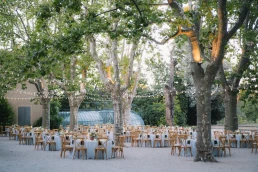 Outdoor wedding reception tables arranged beneath mature trees at Château Valmousse