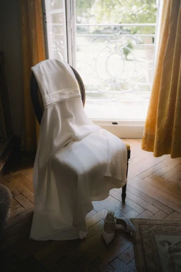 Bride seated beside a window with her veil over her face at Château Valmousse