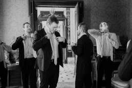 Black-and-white photograph of groomsmen helping the groom dress at Château Valmousse