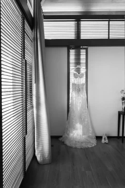 Black-and-white silhouette of a wedding dress hanging beside a window in Phuket, Thailand