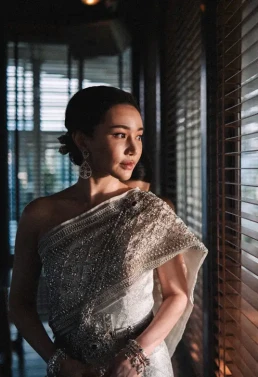 Bride in traditional Thai dress standing beside wooden shutters in Phuket, Thailand