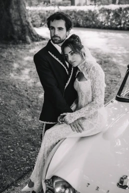Black-and-white portrait of the bride and groom embracing beside a vintage car in Provence