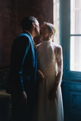 Bride and groom kissing beside a window during their elopement in Provence