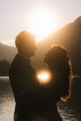 Silhouetted couple facing each other beside a lake at sunset in Scotland