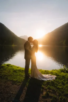 Silhouetted couple embracing beside an alpine lake at sunset in Switzerland