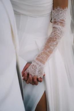 Bride and groom holding hands, highlighting her lace wedding sleeve in Switzerland