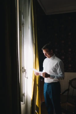Groom reading a letter by the window before his elopement in Switzerland