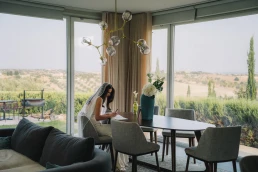 Bride getting ready in a bright room overlooking the countryside