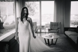 Smiling bride in her wedding dress standing beside a large window